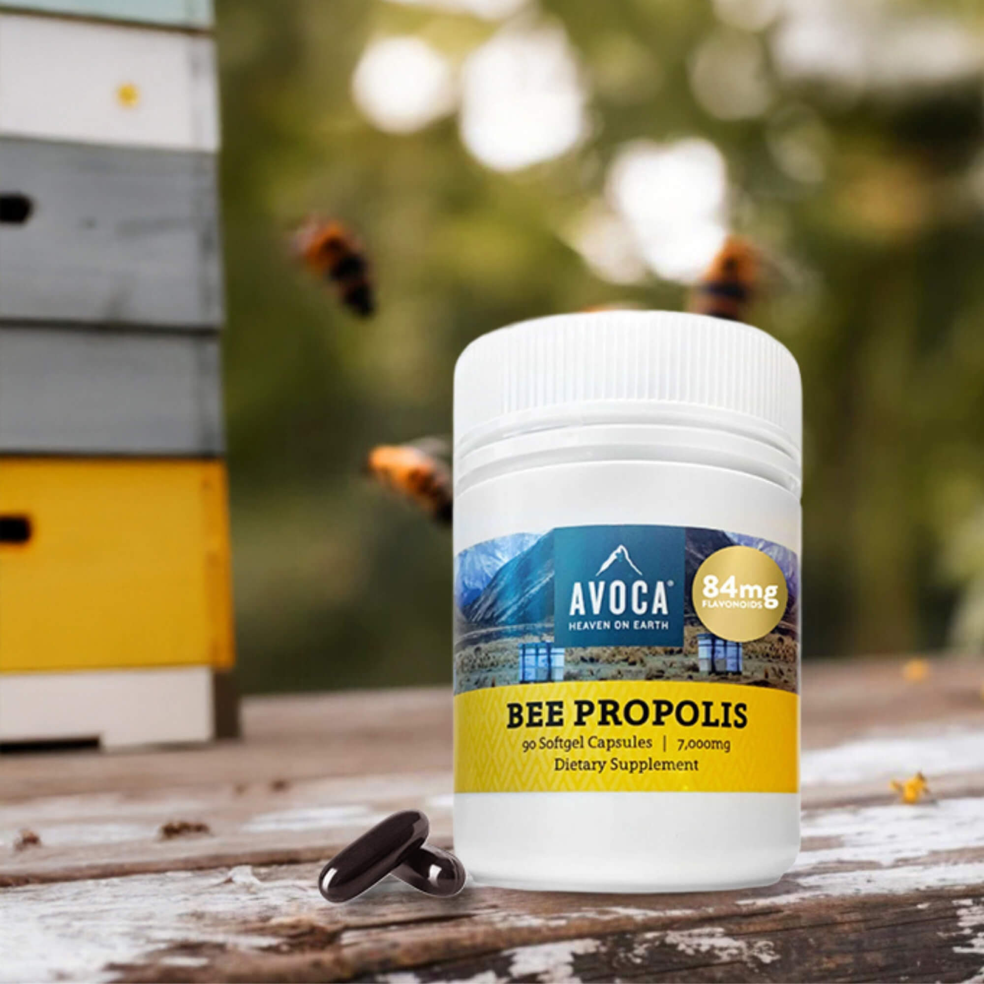 Avoca Bee Propolis supplement bottle with bee hive and bees in the background
