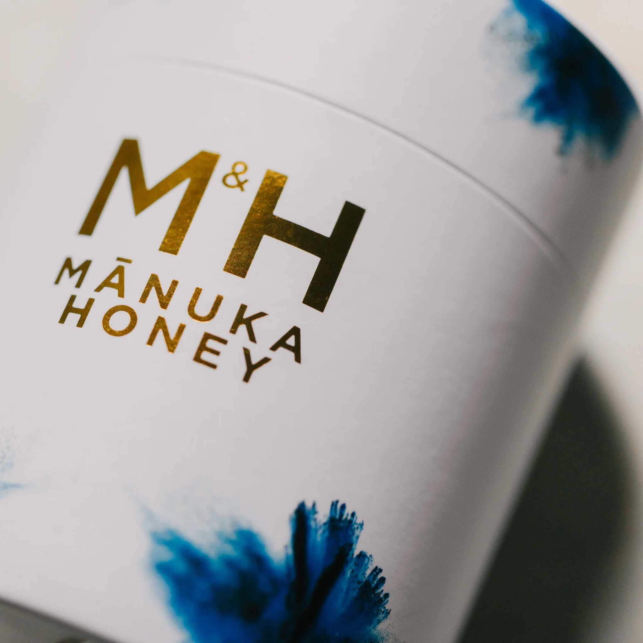 M&H Manuka Honey UMF 26+ container with 'M&H' branding on a white background