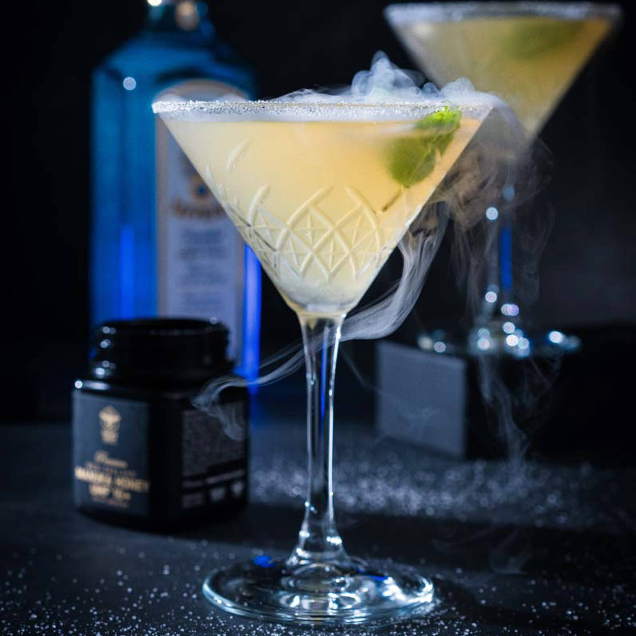 A glass of cooktail on the table with Manuka South Manuka Honey 250g jar