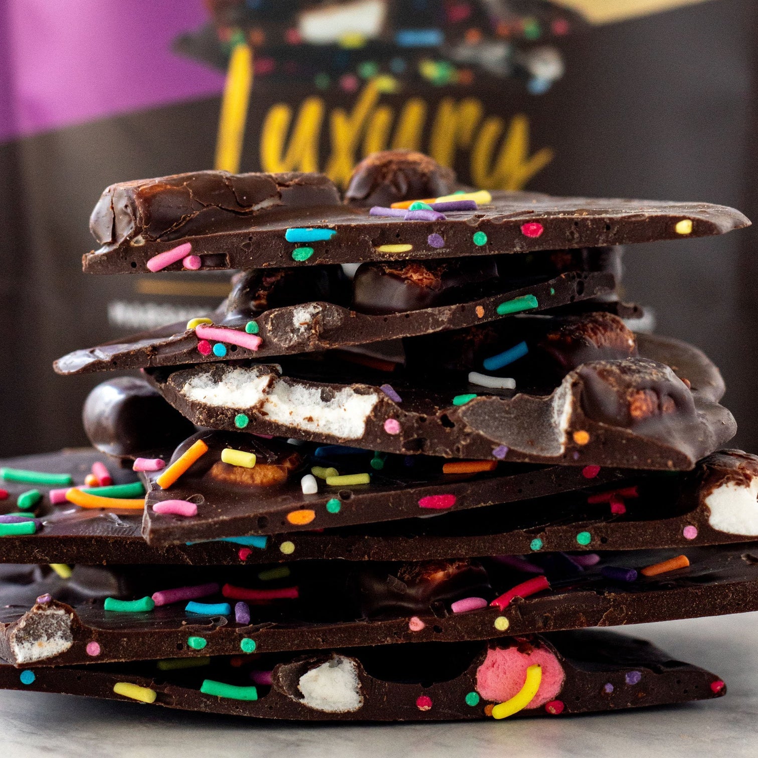 Stack of The Remarkcable Chocolate bark mashmallow and crunchy sprinkles chocolate bark on a dark background
