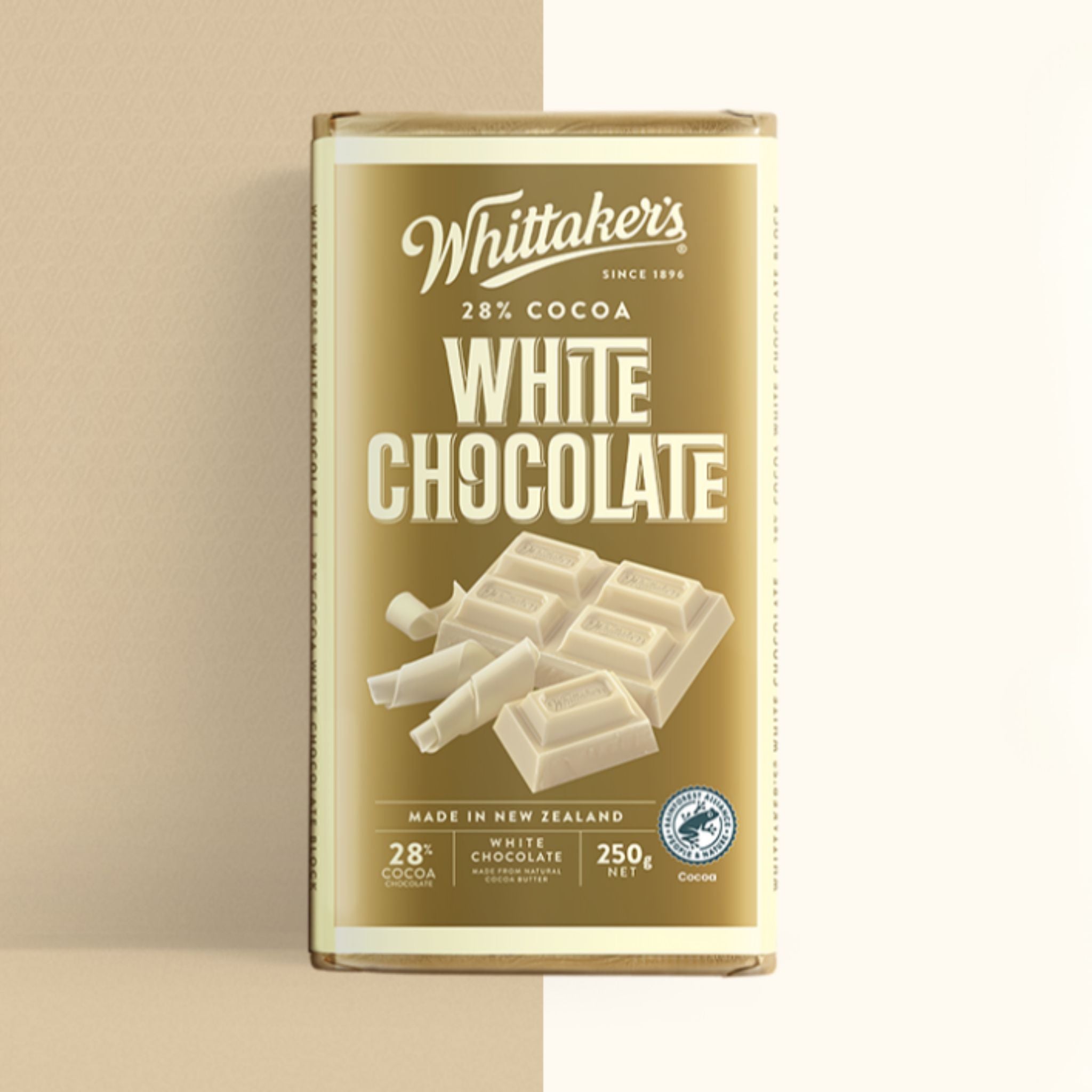 A single bar of Whittaker's 28% Cocoa White Chocolate in its original packaging, standing upright against a minimalist beige background.