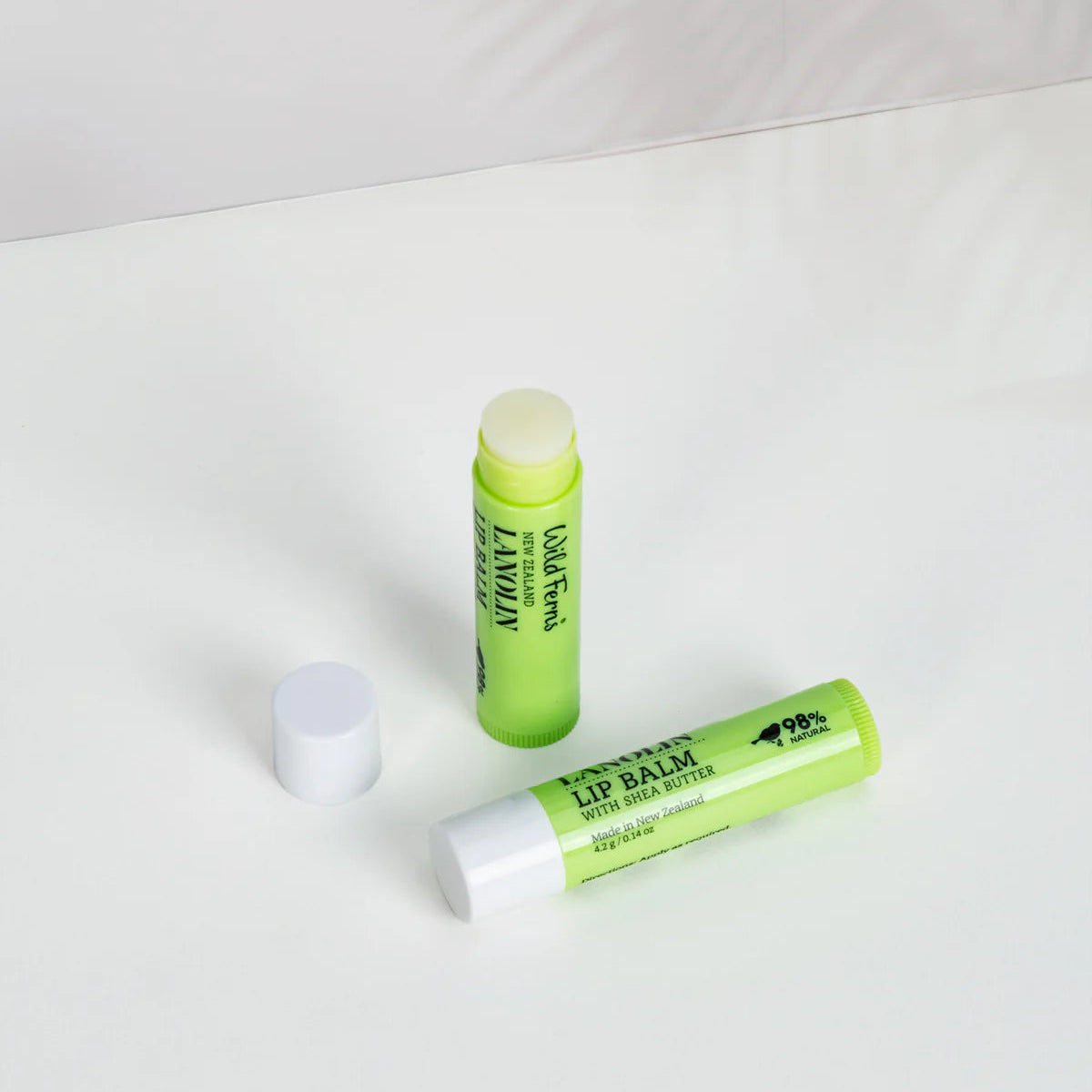 Two green Wild Ferns Lanolin lip balm tubes on a white background