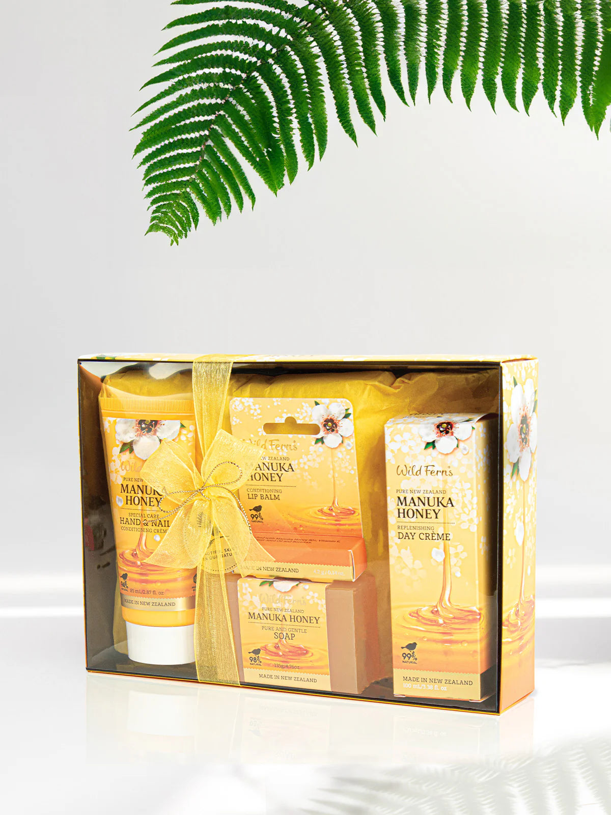 Gift set with Wild Fern's Manuka Honey products on a white background with a fern leaf.