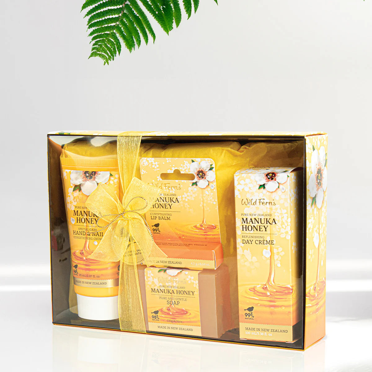 Gift set with Wild Fern's Manuka Honey products on a white background with a fern leaf.