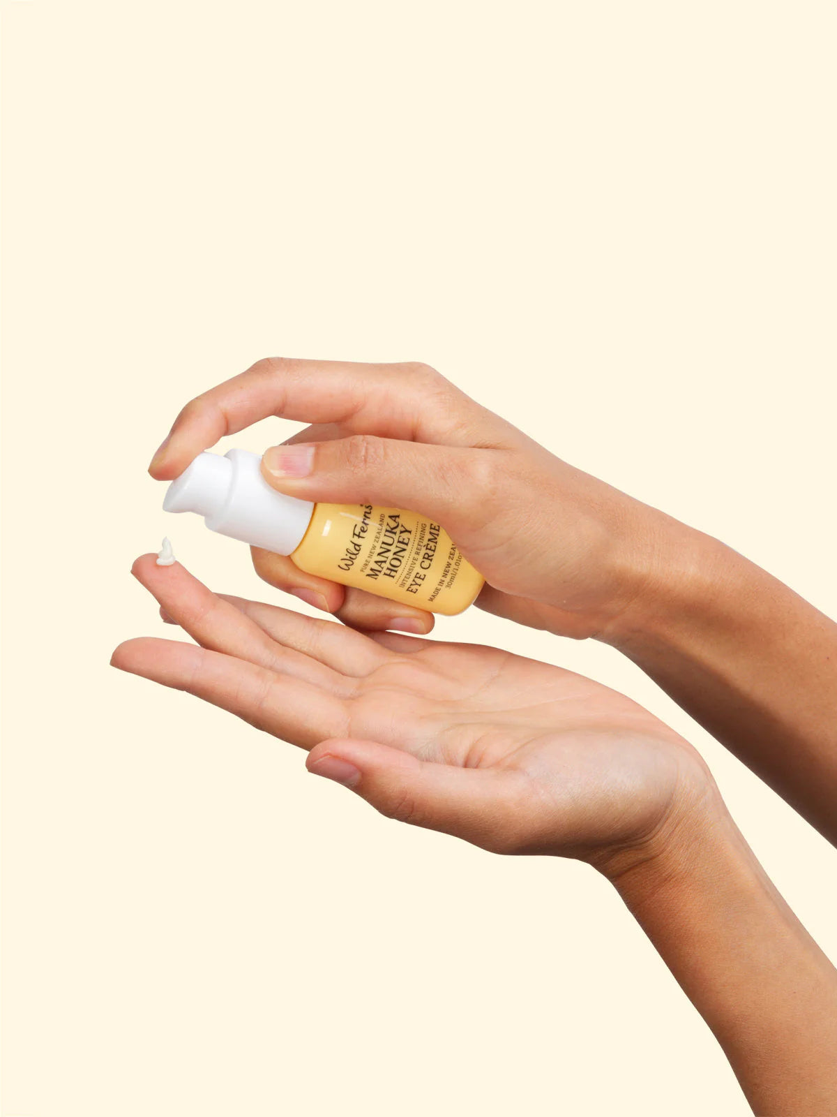 Hand holding a bottle of Wild Ferns Eye Creme with a beige background