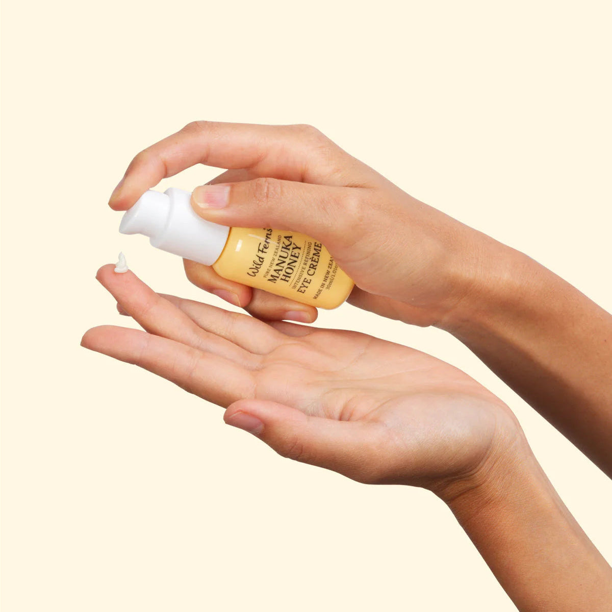Hand holding a bottle of Wild Ferns Eye Creme with a beige background