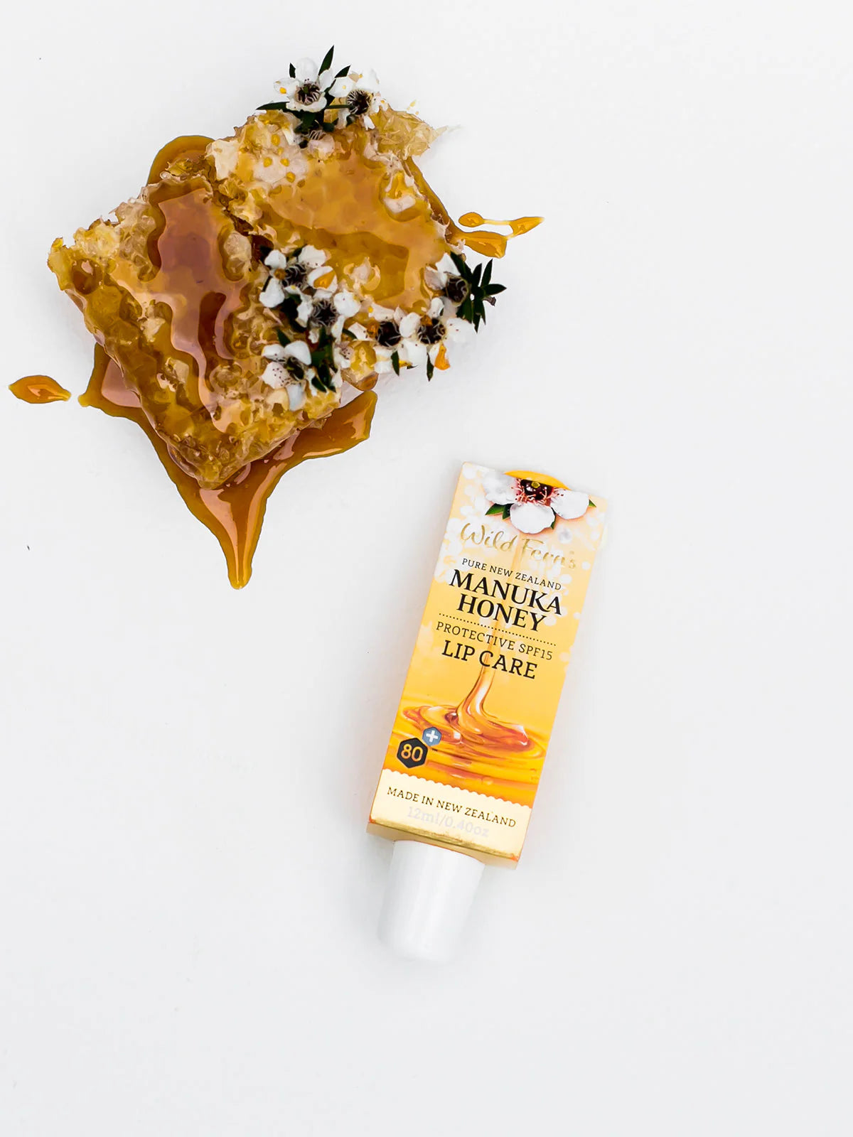 Manuka honey lip care with honeycomb and flowers on a white background
