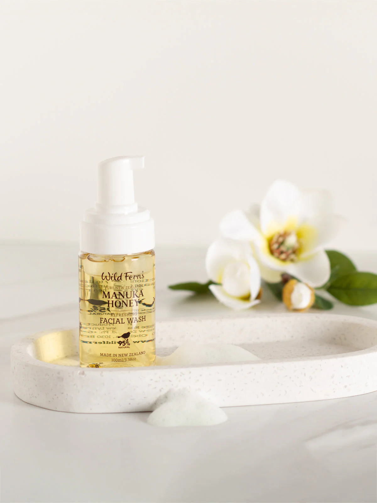 Wild Ferns Manuka Honey Facial wash bottle with flowers on a white surface