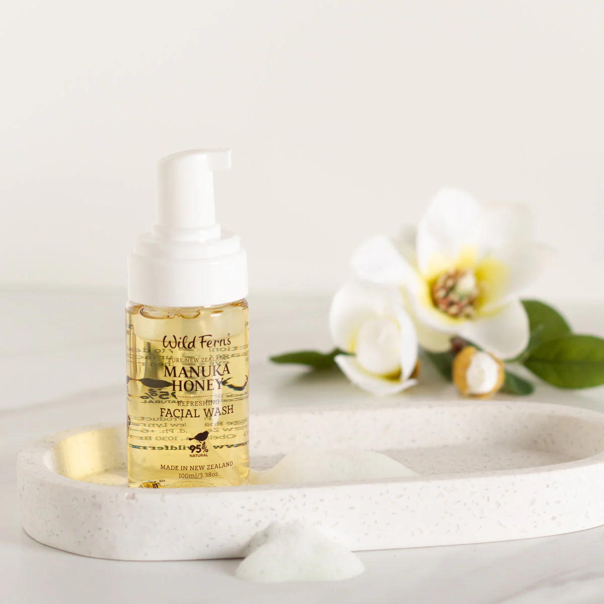 Wild Ferns Manuka Honey Facial wash bottle with flowers on a white surface