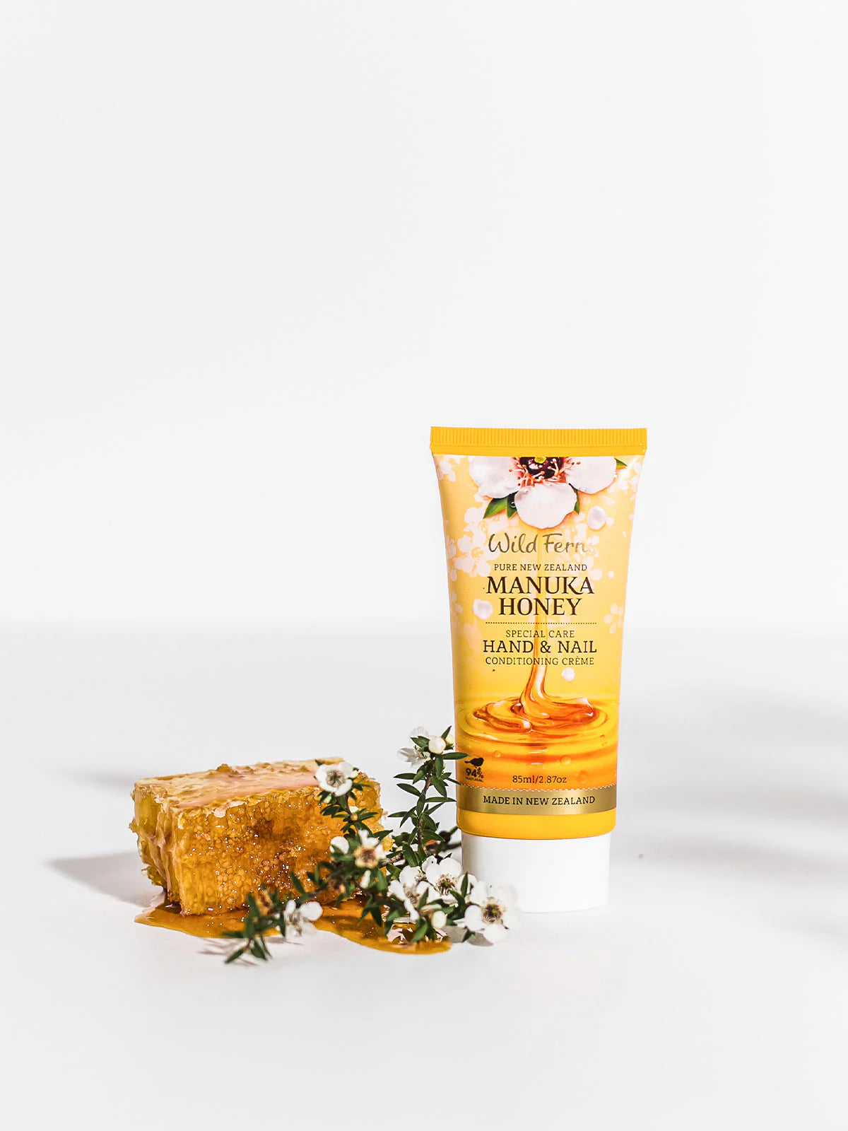Wild Fern's Manuka Honey Hand and Nail Creme with honeycomb and flowers on a white background
