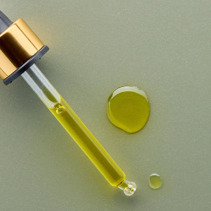ANtipodes Divine Gold dropper with yellow liquid on a light green background