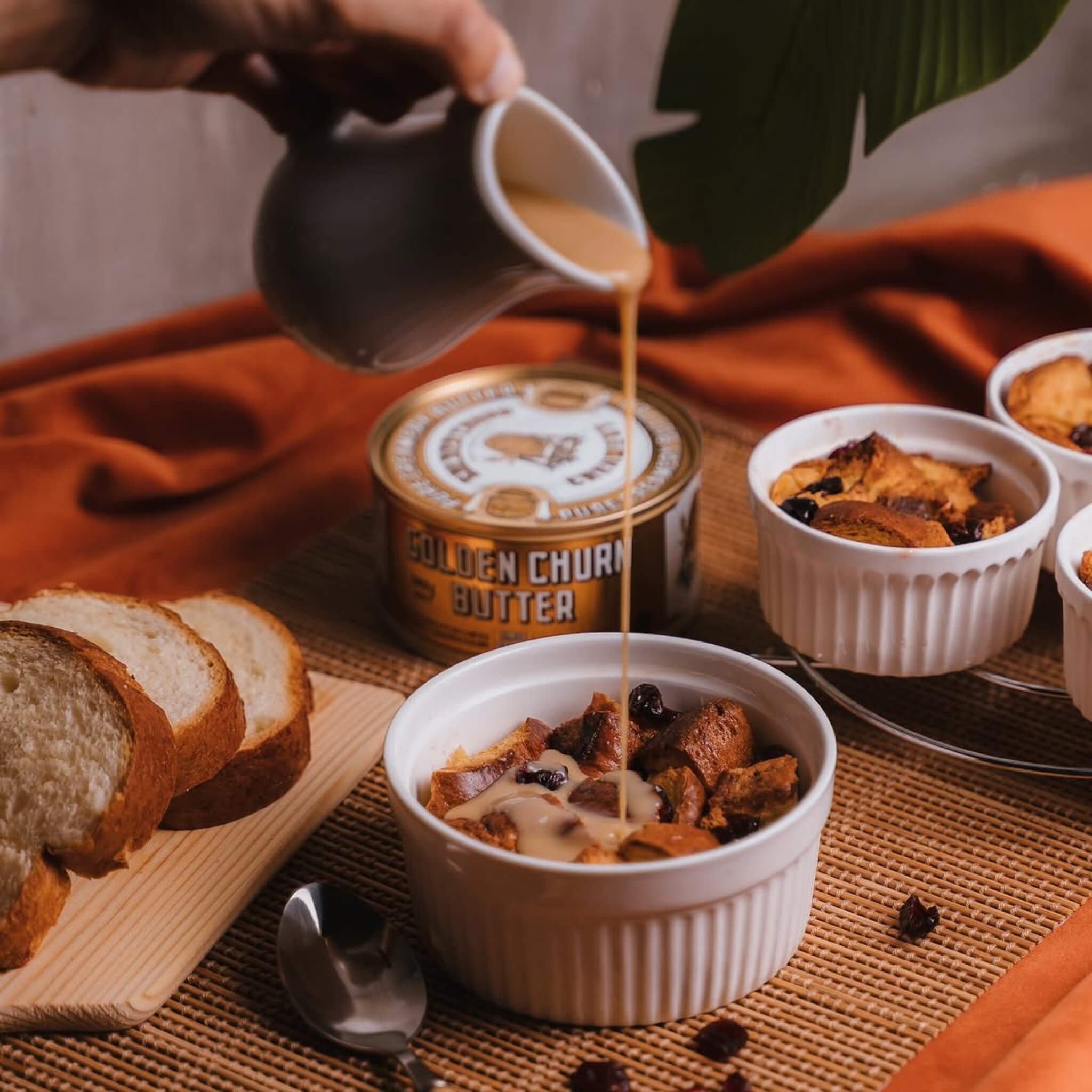 Person pouring butter into a bowl of cereal with bread and Golden Churn butter in the background