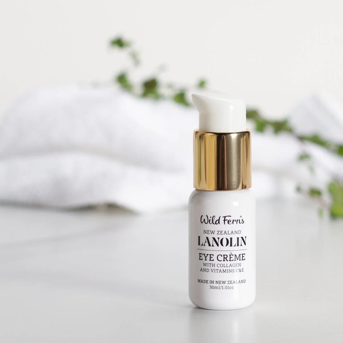 White bottle of Wild Ferns Lanolin Eye Crème with gold cap on a light background