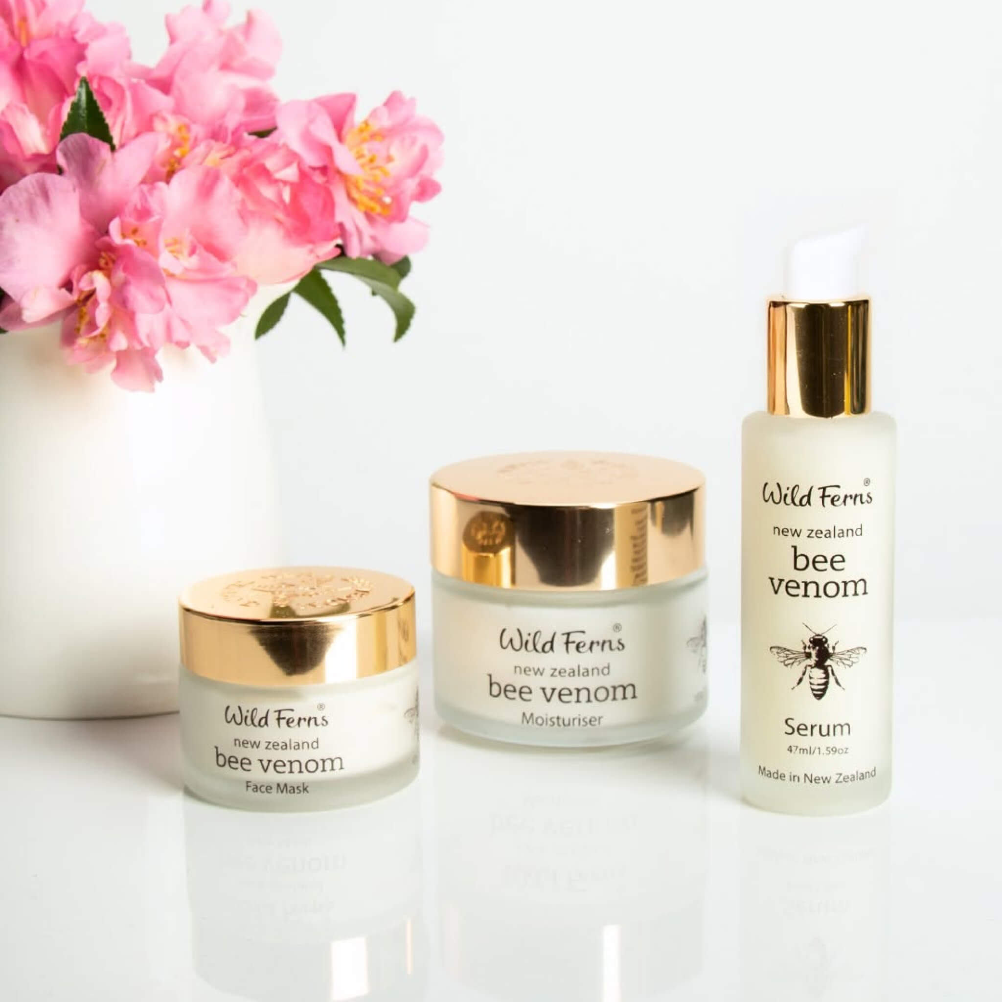 Wild Ferns New Zealand bee venom skincare products with pink flowers in the background