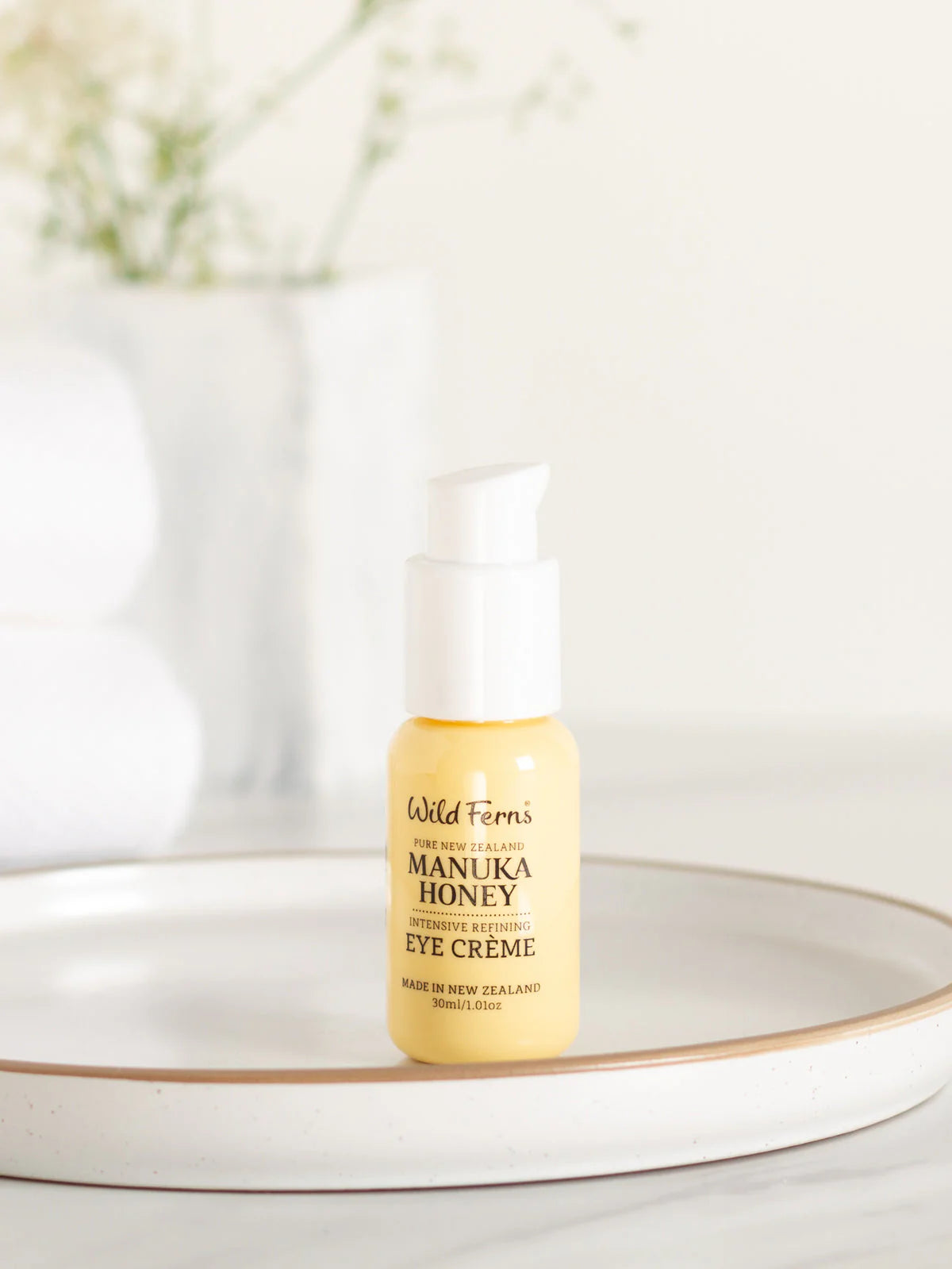Wild Fern's Manuka Honey Eye Crème bottle on a white surface with a blurred background