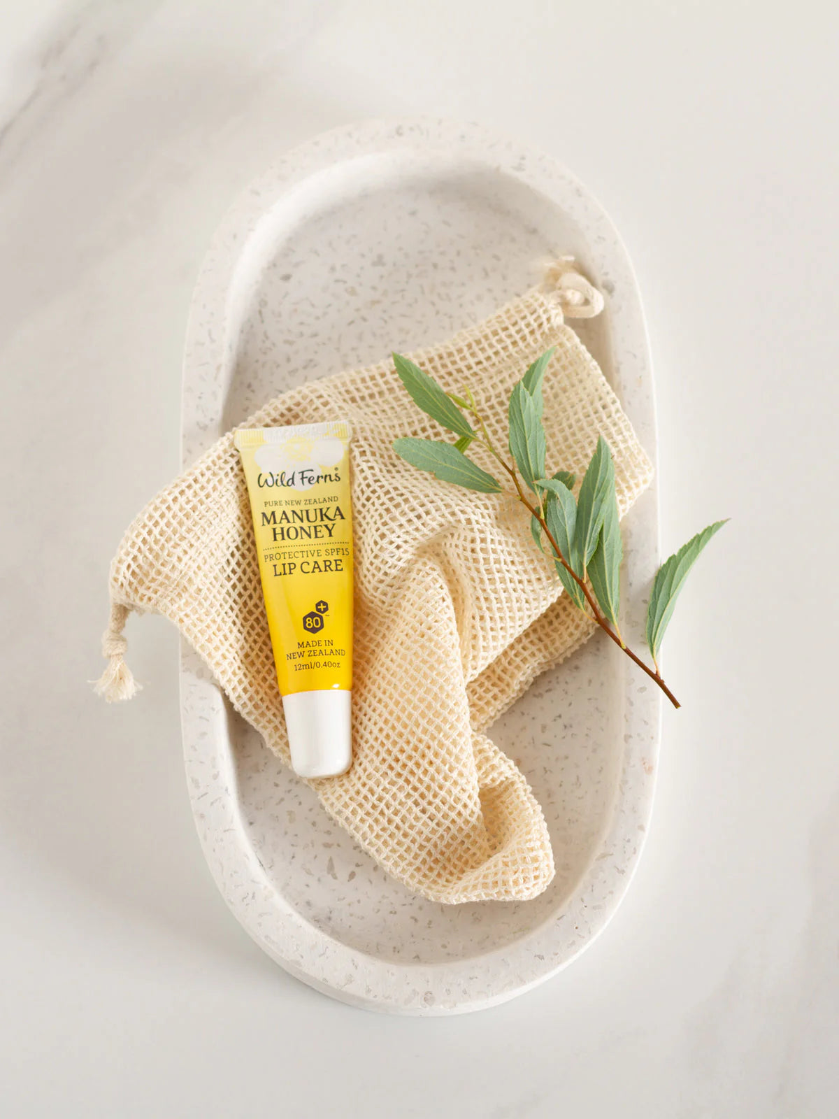 Lip balm with 'Manuka Honey' on a textured stone surface