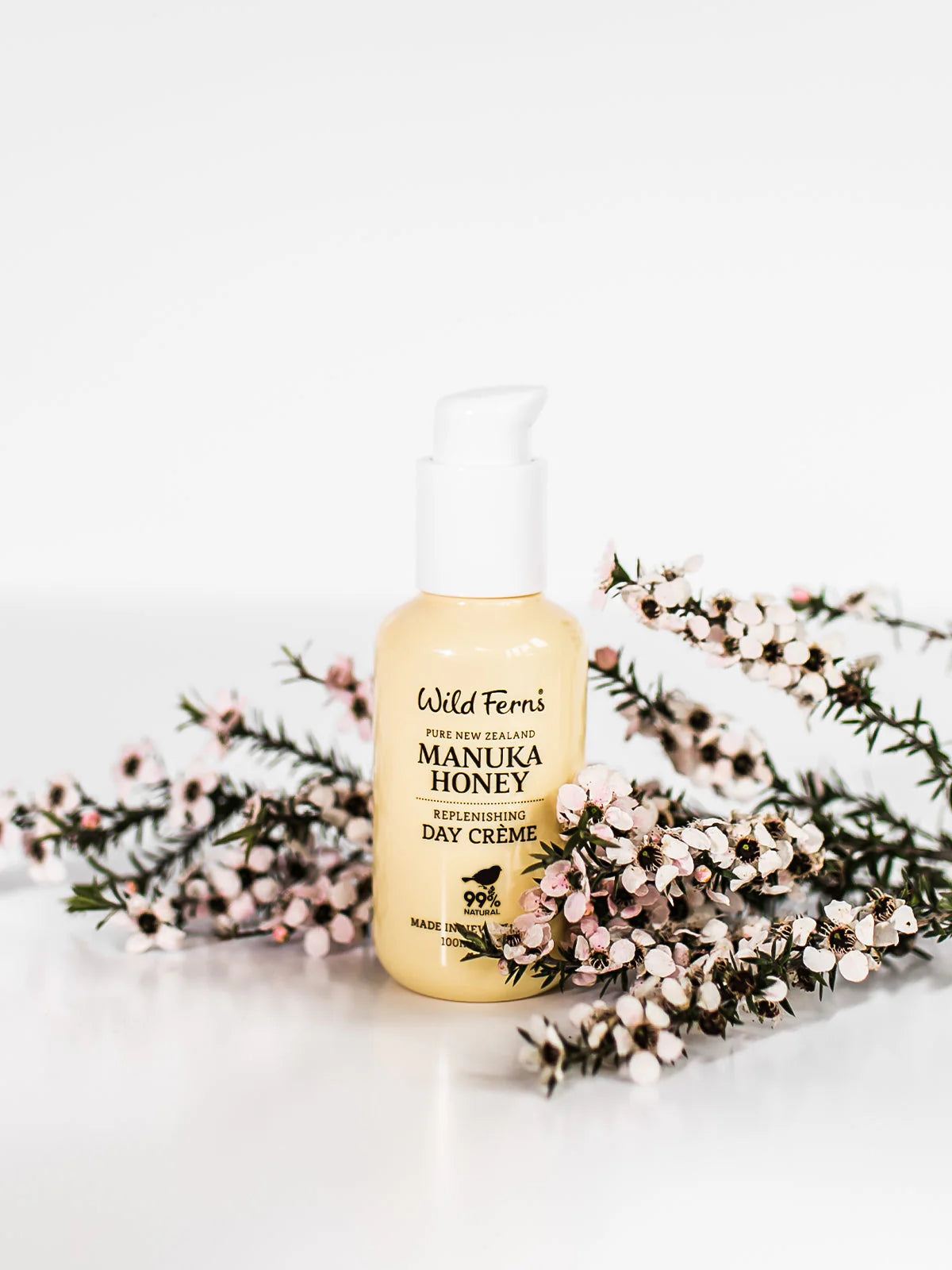 Manuka Honey Day Creme bottle with floral arrangement on a white background