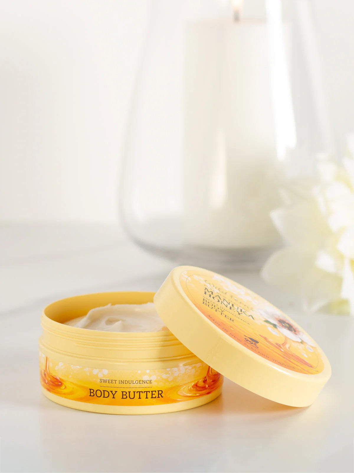  A container of Wild fern's body butter with a blurred candle in the background