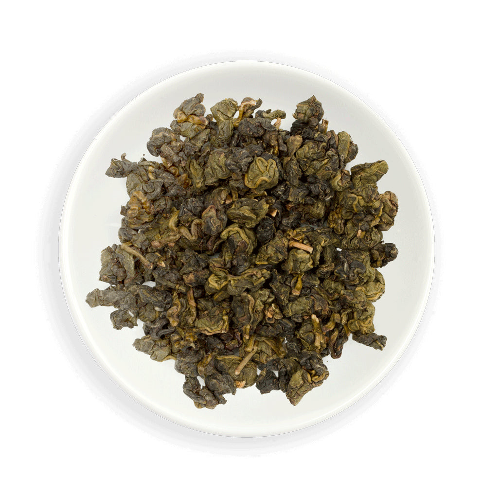 Dry green Zealong Oolong tea leaves on a white plate
