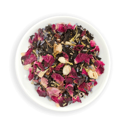 Assorted dried Zealong  tea leaves with flowers and herbs in a white bowl on a white background