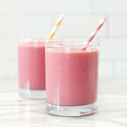Two glasses of pink smoothie with straws on a white background